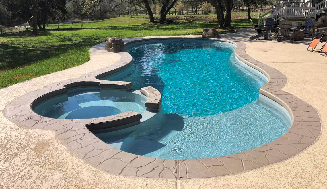 Leisure Pools Allure large fiberglass swimming pool with built-in spa and splash deck