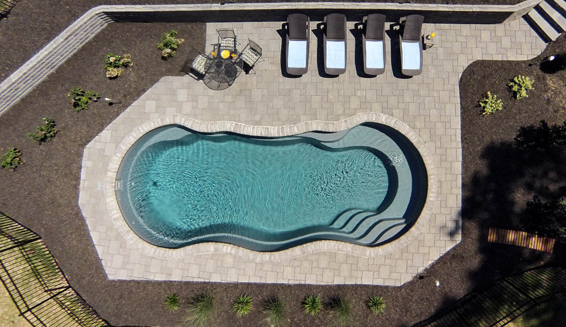 Leisure Pools Riviera composite fiberglass freeform swimming pool with deep-end swim-out