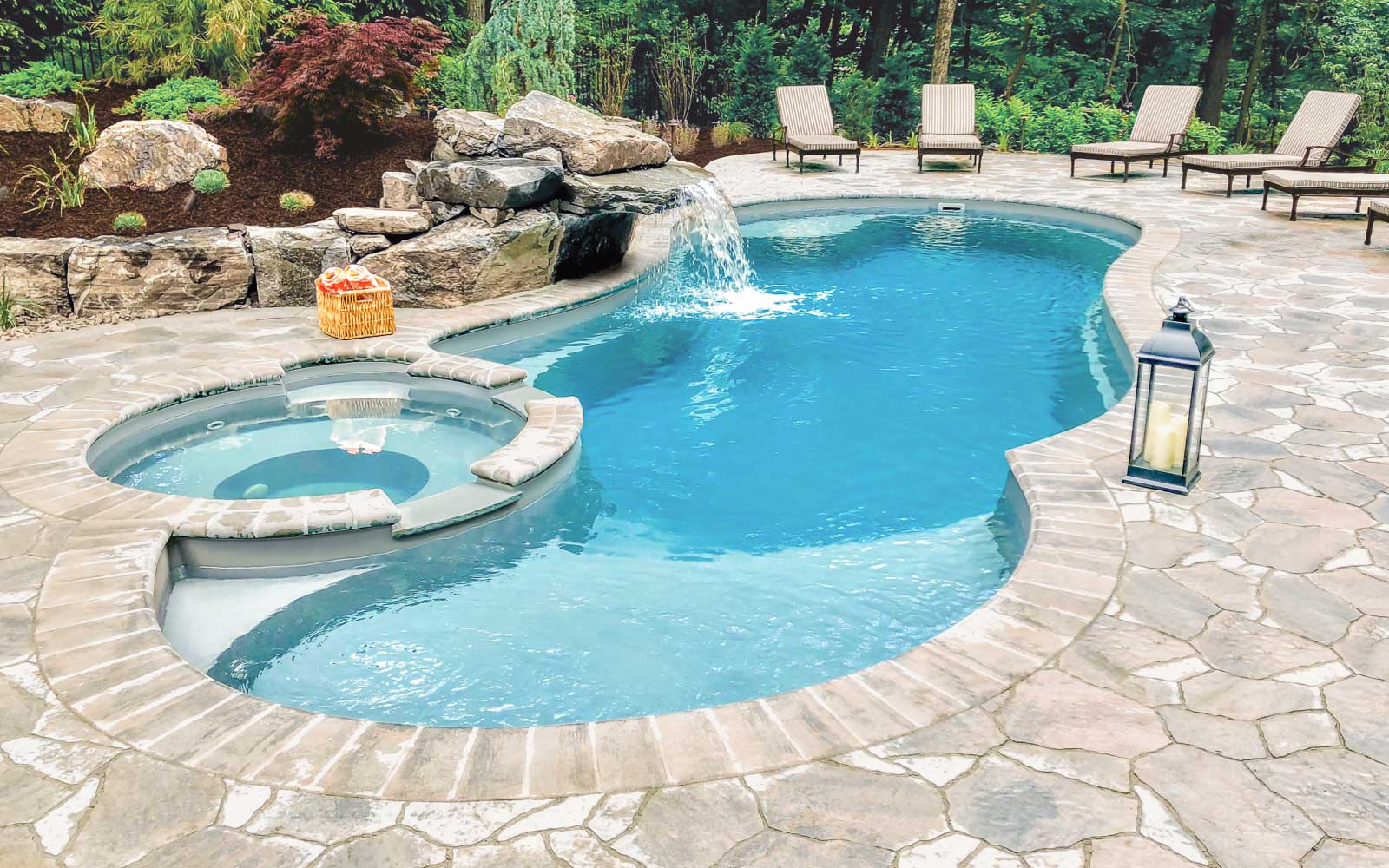 Leisure Pools Allure freeform fiberglass swimming pool with built-in spa and splash deck