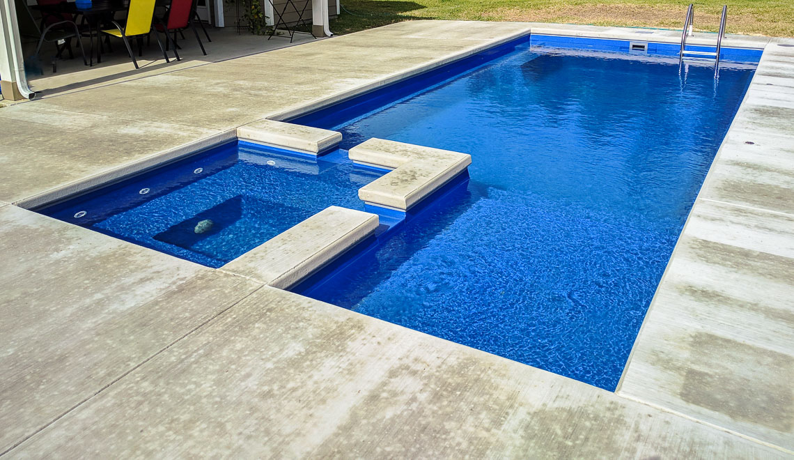 Leisure Pools Limitless fiberglass swimming pool with built-in spa and tanning ledge