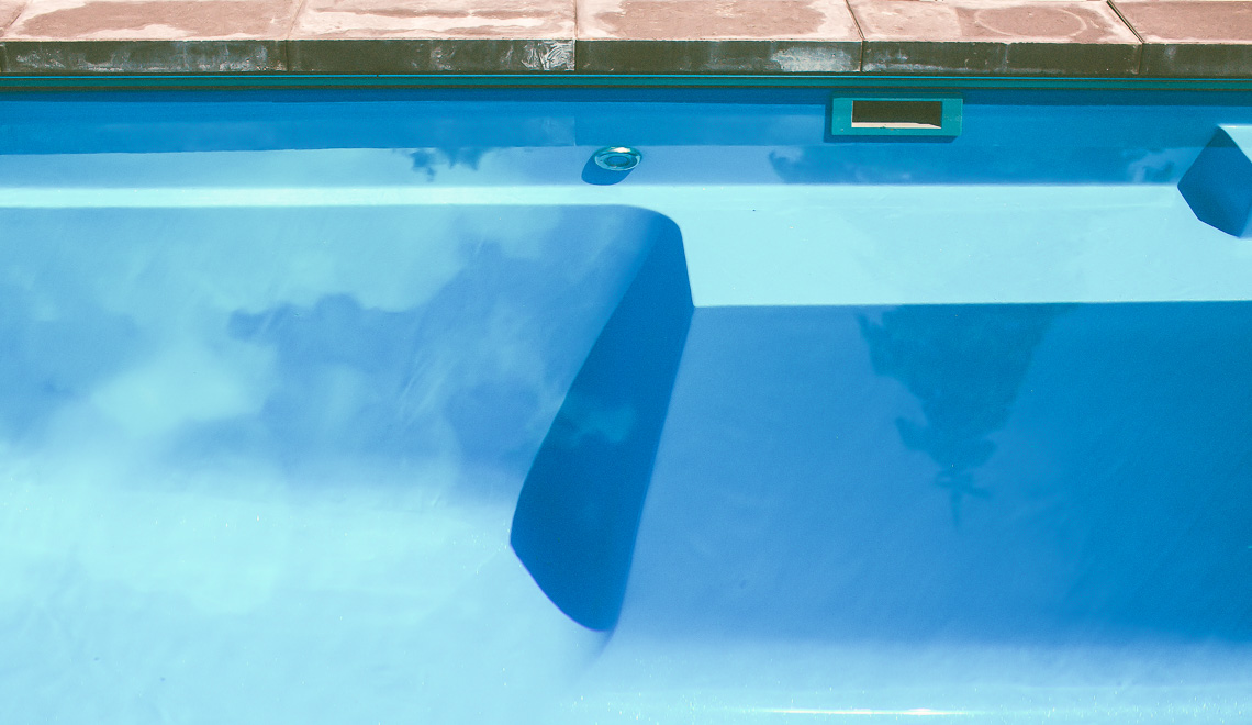 Leisure Pools Limitless precast fiberglass swimming pool with built-in spa, splash deck and bench